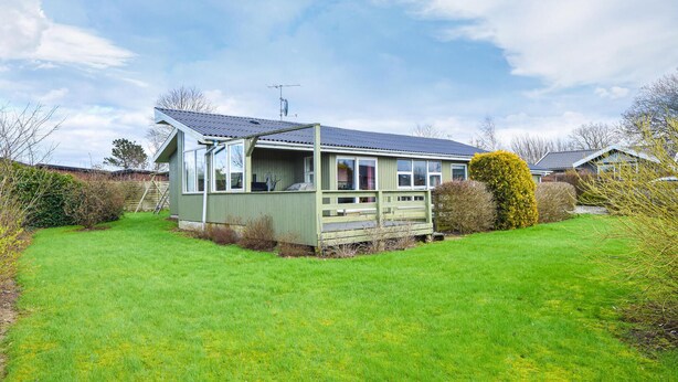 Ein einstöckiges Haus mit einer großen Veranda, einer Garage und einem gepflegten Rasen.