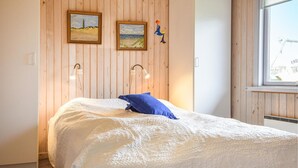 Ein Schlafzimmer mit einem Bett, zwei Wandlampen und zwei gerahmten Bildern.