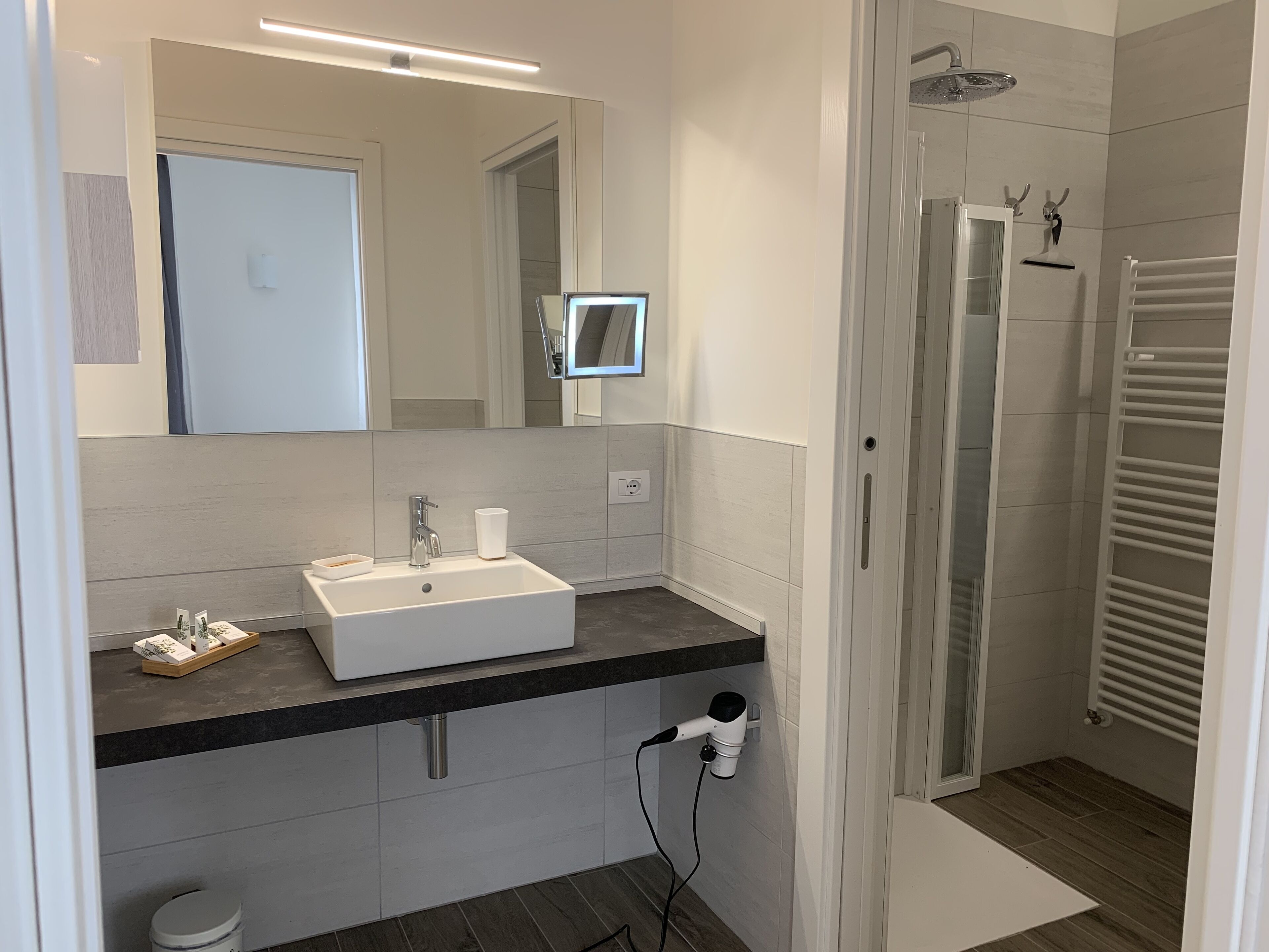 A modern bathroom with a white sink, mirror, and shower.
