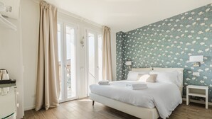 A bedroom with a bed, bedside tables, and a view through the glass doors. - Casa Baci (Lazise)