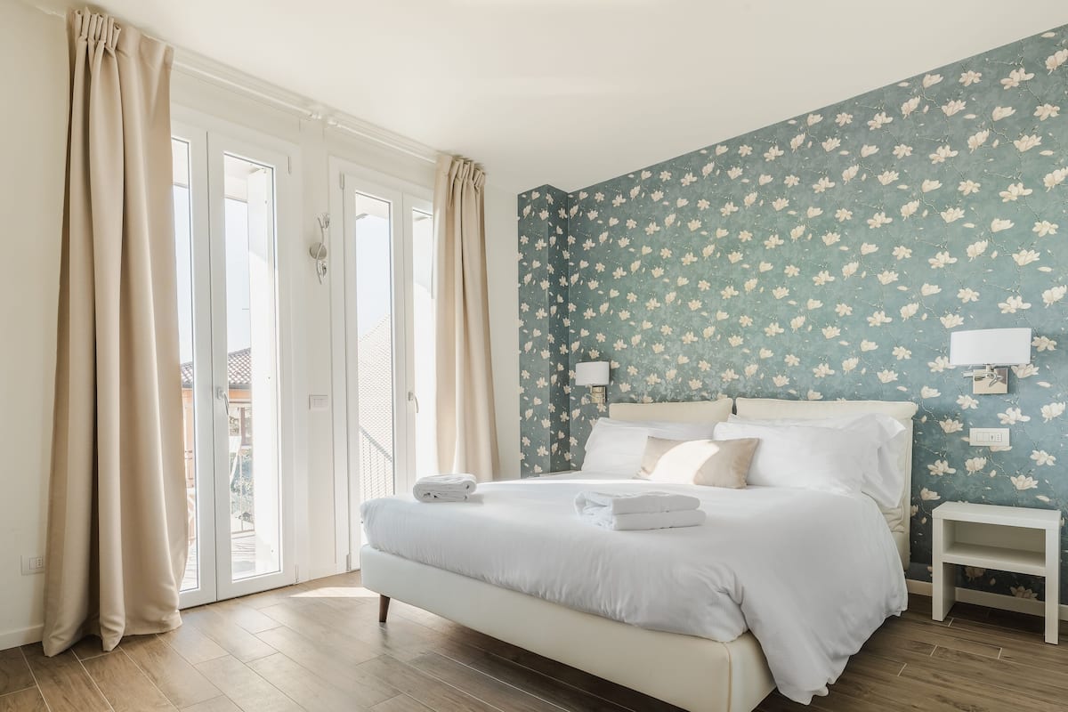 Un dormitorio con cama, mesitas de noche y vistas a través de puertas de vidrio.