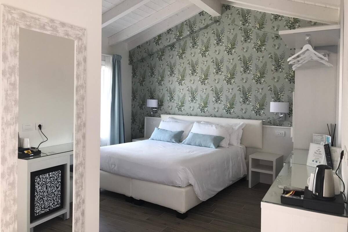 Un dormitorio con cama, mesitas de noche, un espejo y un aparador.