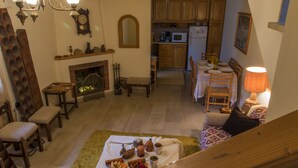 A cozy living room with a fireplace, wooden furniture, and a dining area with a table set for four.
