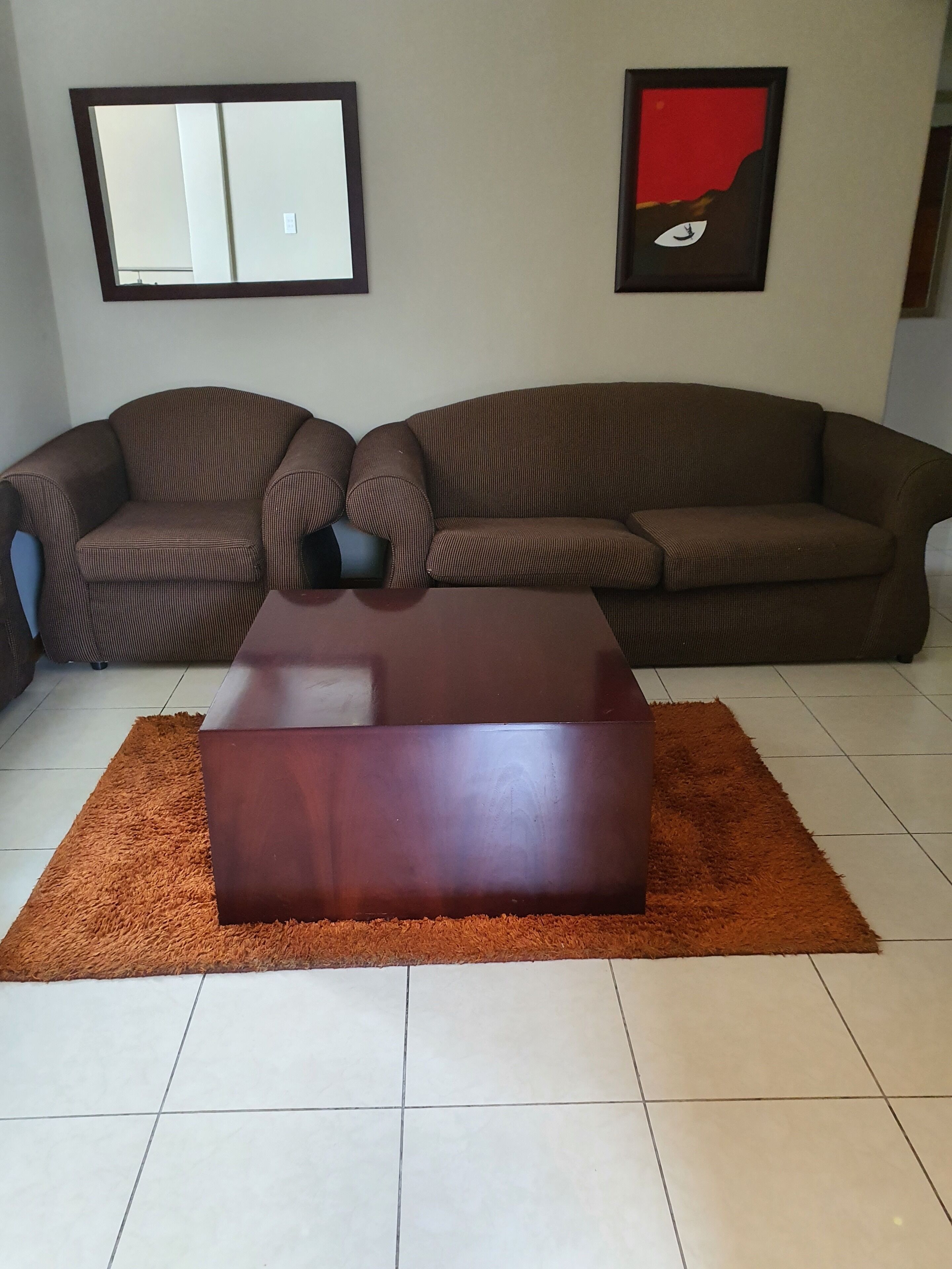 Una sala de estar con dos sofás marrones, una mesa de centro de madera y una alfombra.