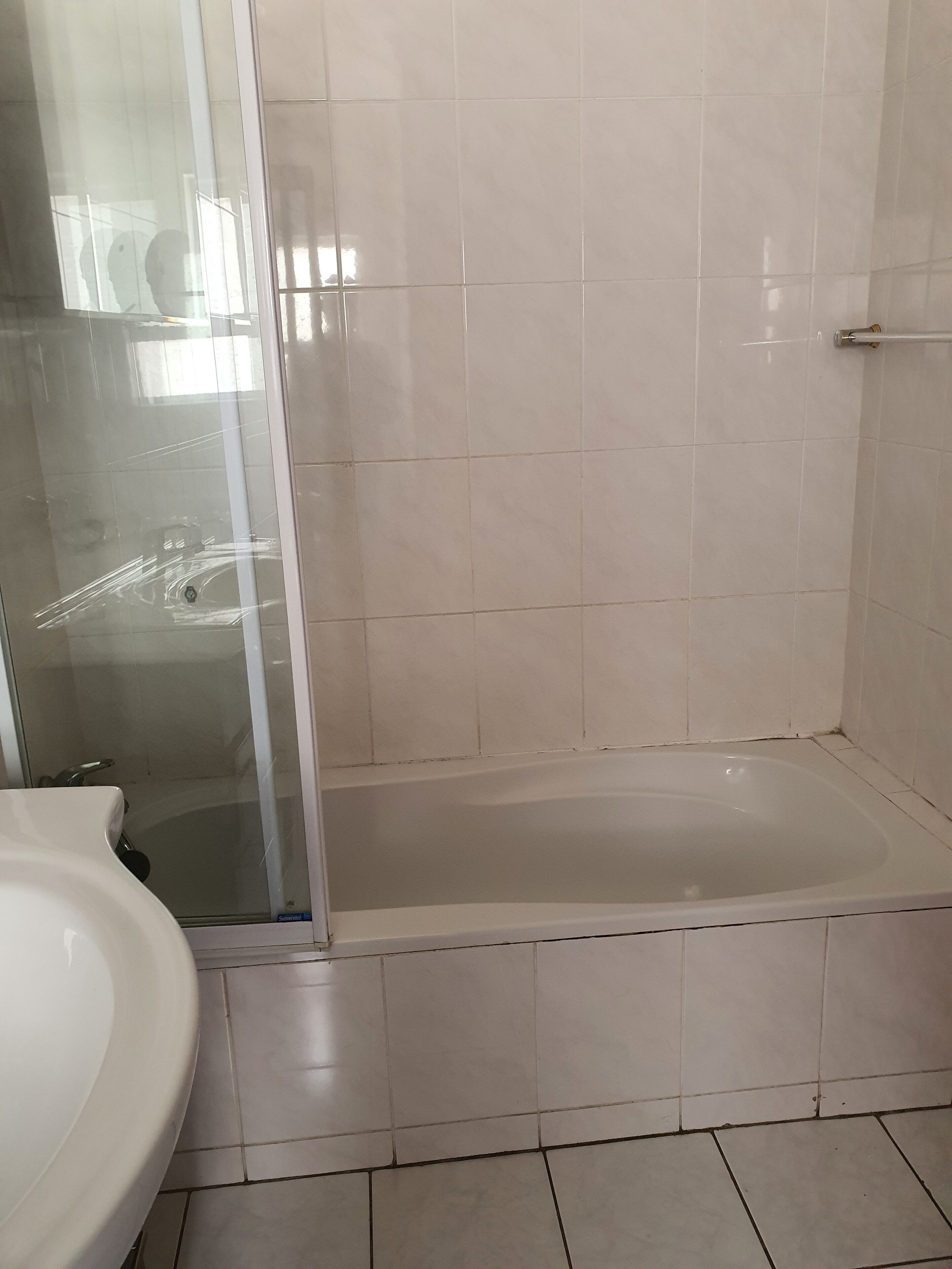 Une salle de bain avec une douche à parois de verre, un lavabo blanc et une baignoire.