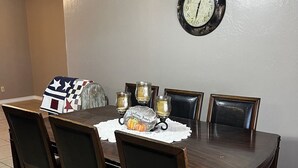 Un tavolo da pranzo con quattro sedie, una sveglia appesa al muro e un sottopiatti decorato con una zucca.