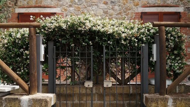 Un edificio de piedra con entrada porticada, contraventanas de madera y un cartel que indica las plazas de estacionamiento 3C y 4C.