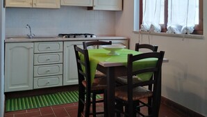 Una cocina con armarios blancos, una estufa a gas y un comedor con una mesa y sillas.