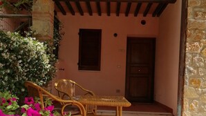 Un patio con mobiliario de mimbre, un muro de piedra y una puerta.