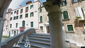 Una escalera conduce a un edificio de estilo arquitectónico clásico, con columnas y ventanas de arco.