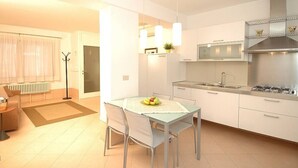 Una cocina moderna con armarios blancos, una estufa a gas y un comedor con mesa y sillas.