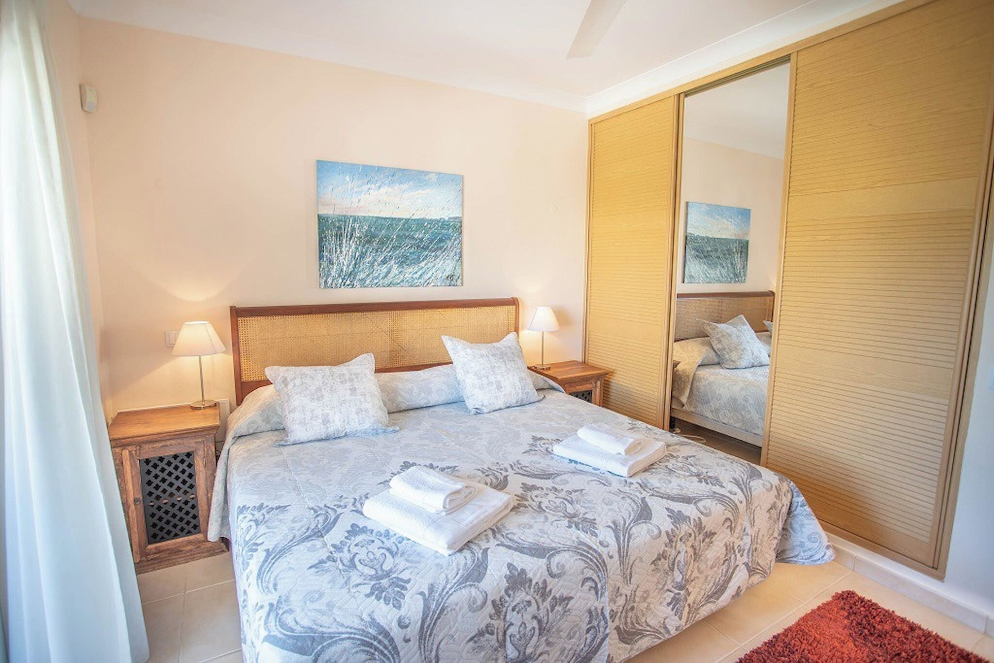 Una camera da letto con un letto grande, due comodini con lampade, un armadio e due quadri appesi al muro.