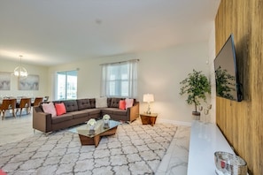 Relax in this stylish living room with a sectional sofa, flat-screen TV, and dining area.