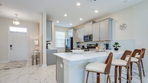 Uma cozinha moderna com uma ilha central, banquetas e eletrodomésticos embutidos.