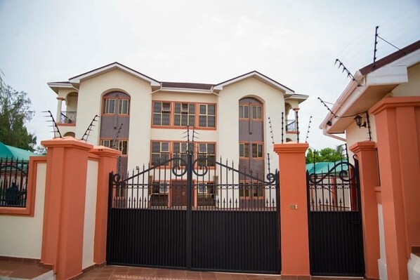 A two-story house with a gated entrance, large windows, and a balcony.