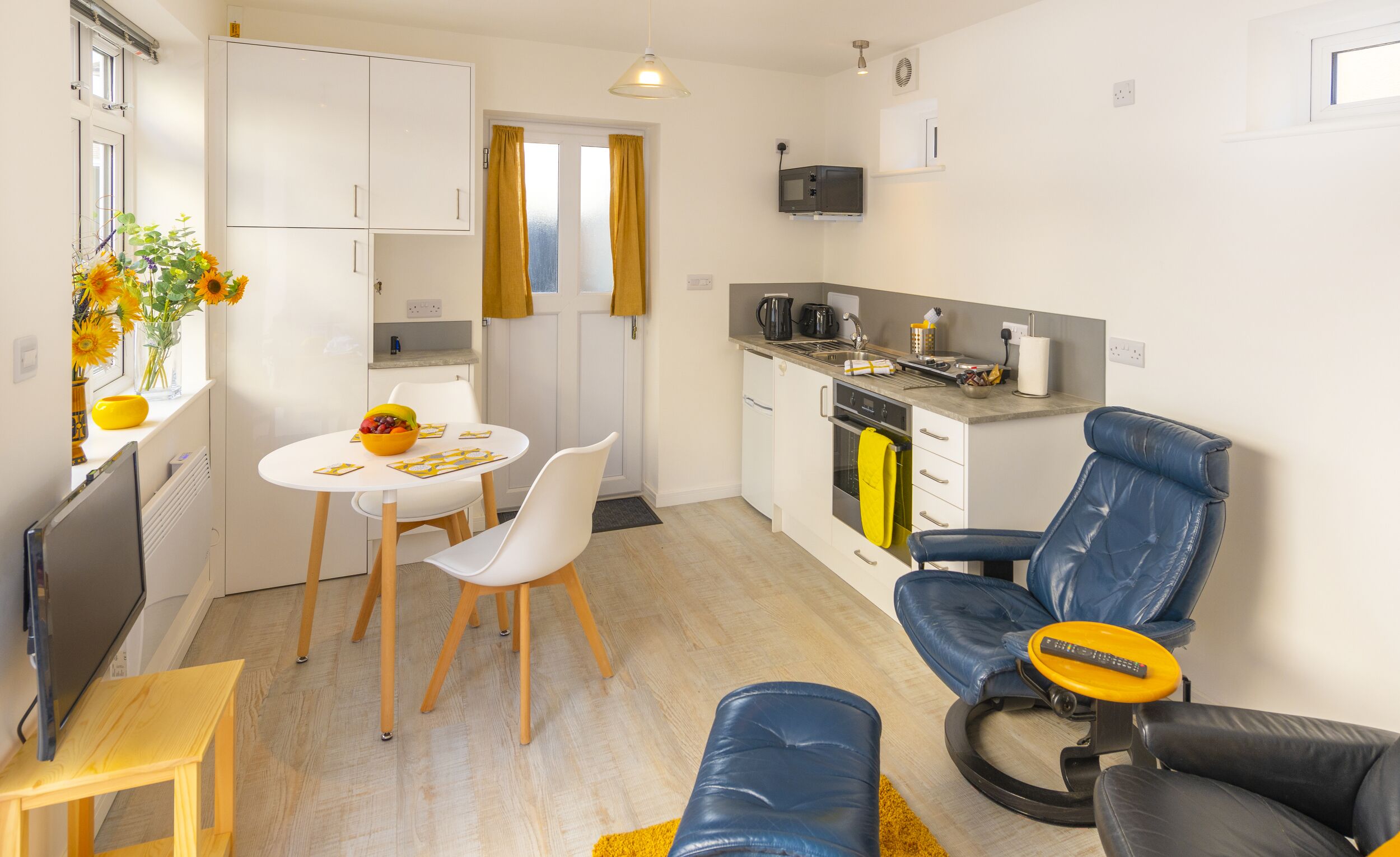 Un espace de vie compact comprenant un coin repas, une kitchenette et un coin salon.