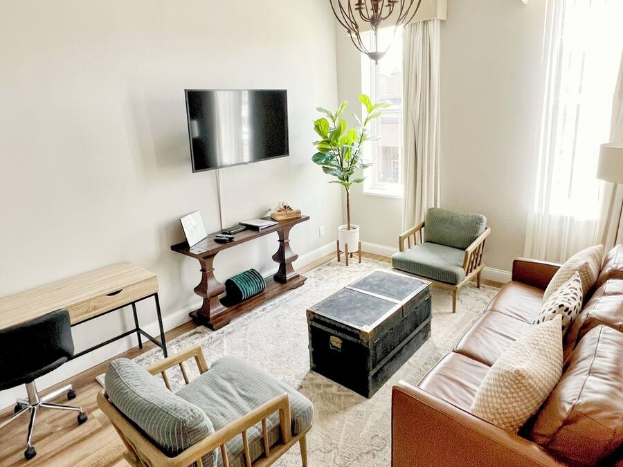A modern living room with a flat-screen TV, a wooden desk, a comfortable sofa, and a coffee table.