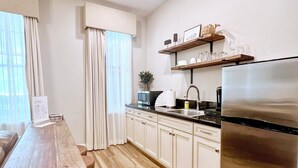 Una cocina moderna con una mesa de madera, taburetes de bar, un refrigerador y un lavamanos.