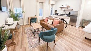 Un apartamento moderno con sala de estar, comedor y cocina. Hay un sofá, una mesa de centro y una mesa de comedor. La cocina cuenta con un refrigerador, estufa y microondas.