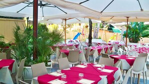 An outdoor dining area with tables covered in red tablecloths and white chairs. - Apartment Bruno at Principina a Mare (Principina a Mare)