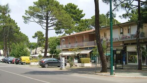 A street view with a building featuring a balcony with outdoor seating, a pizza restaurant, and a parked car. - Apartment Bruno at Principina a Mare (Principina a Mare)