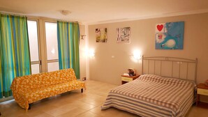 A bedroom with a bed, a sofa, a nightstand, and a window with curtains. - Apartment Bruno at Principina a Mare (Principina a Mare)