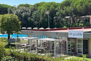 A restaurant with outdoor seating, a pool in the background, and a sign that reads 'rio grande'. - Apartment Bruno at Principina a Mare (Principina a Mare)