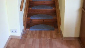 Een houten trap met beklede treden die naar een deur leidt.