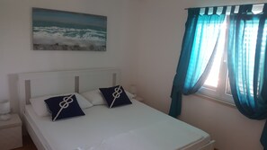 Une chambre à coucher avec un lit, des oreillers, un tableau et des rideaux.