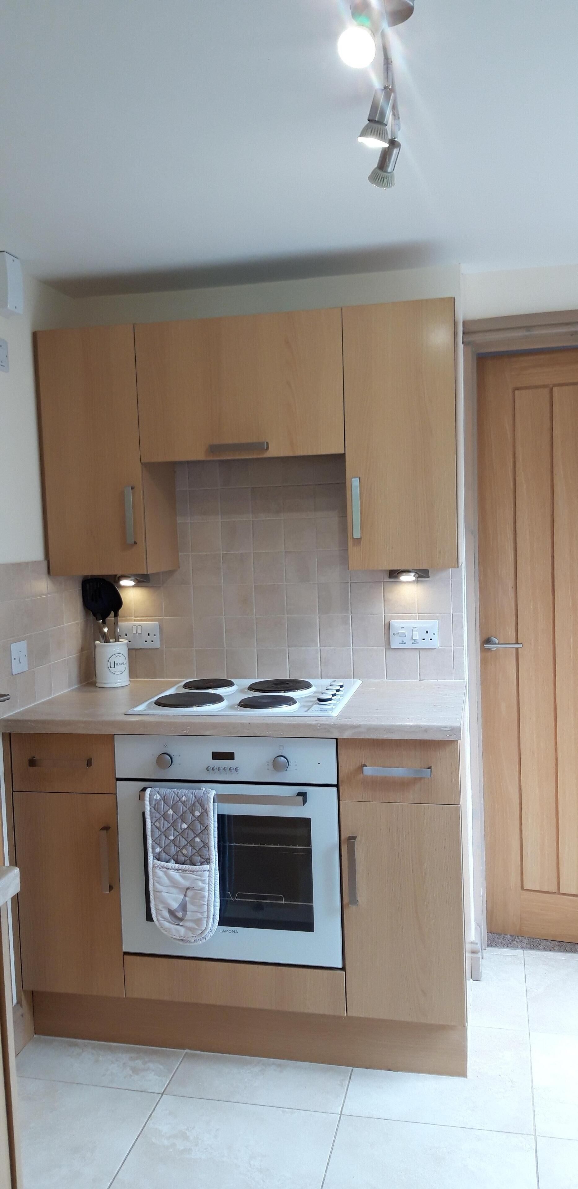 A kitchen with wooden cabinets, a stove, and a tiled backsplash.