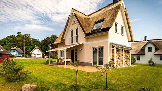 A house with a thatched roof, large windows, and a covered patio area. - Fuchsbau (Zirchow)