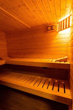 A wooden sauna with benches and a wall-mounted clock. - Fuchsbau (Zirchow)