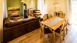 A cozy living room with a sofa, wooden dining table, and chairs. - Fuchsbau (Zirchow)