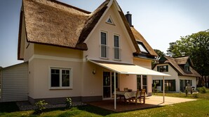 A house with a thatched roof, a covered patio, and a lawn. - Fuchsbau (Zirchow)