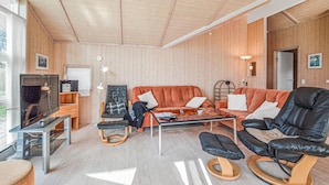 Un salón acogedor con paredes de madera, un sofá de cuero, una mesa de centro de vidrio y una televisión.