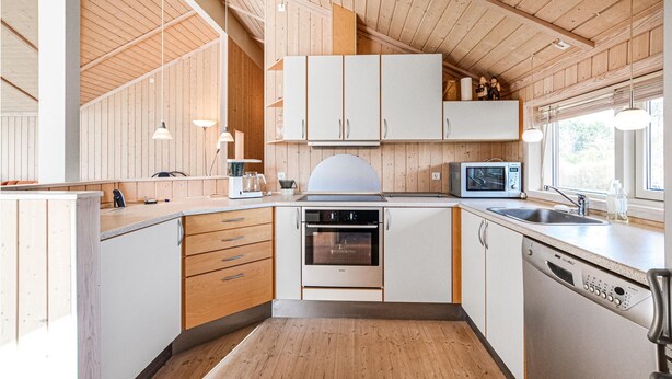 Una cocina moderna con armarios de madera, horno empotrado, microondas y lavavajillas.