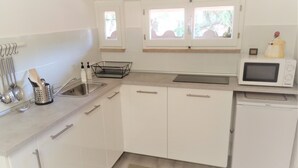 Eine moderne Küche mit weißen Schränken, einer Edelstahl-Spüle, einer Mikrowelle und einem Geschirrspüler.