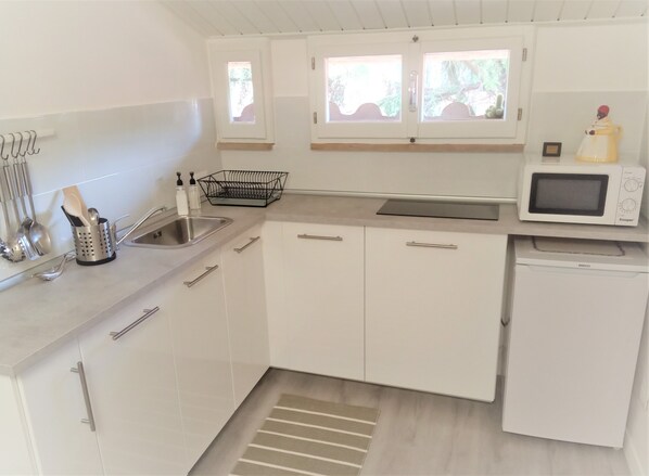 Una cocina moderna con armarios blancos, un lavamanos de acero inoxidable, un microondas y un lavavajillas.