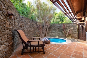 Une terrasse aux murs de pierre, dotée d’une piscine, de meubles en bois et d’une pergola.
