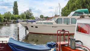 Ein Yachthafen mit mehreren vertäuten Booten, ein überdachter Bereich mit einer blauen Plane und ein Gebäude mit der Aufschrift "Doortje Amsterdam".