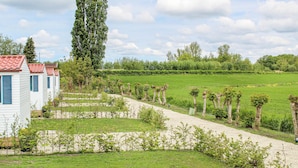 Eine Reihe weißer Gebäude mit roten Dächern, ein Kiesweg und ein grünes Feld mit Bäumen.