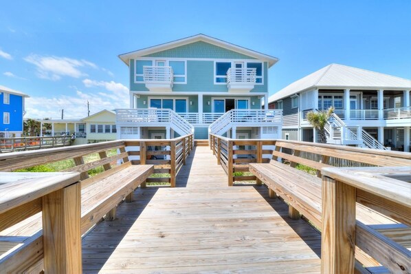 A wooden boardwalk leading to a two-story building with balconies, a covered walkway, and a clear view of the beach. - 🌸Lilypad B: Oceanfront Duplex, 2 Decks w/ Beach Views🌸 (Kure Beach)