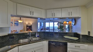 Una cucina moderna con mobili bianchi, piani in granito e lavastoviglie integrata.