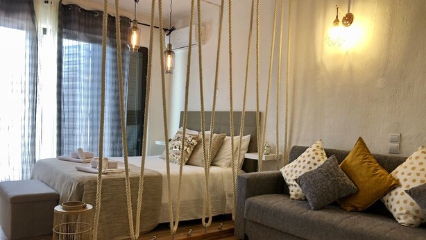 Une chambre à coucher moderne avec un lit, un canapé, un luminaire suspendu et une table de chevet.