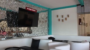 Un salon moderne avec des canapés blancs, un téléviseur à écran plat et un mur décoratif.