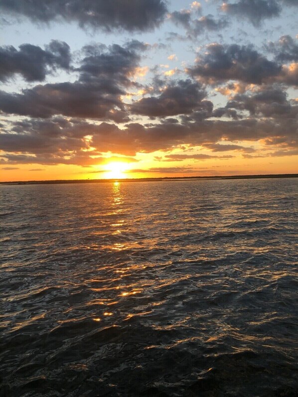 Un atardecer sobre una superficie acuática tranquila con una costa lejana.