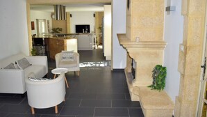 Un saló modern amb un sofà, una butaca i una taula de centre, que dona a una zona de cuina amb una taula de dinar i cadires.