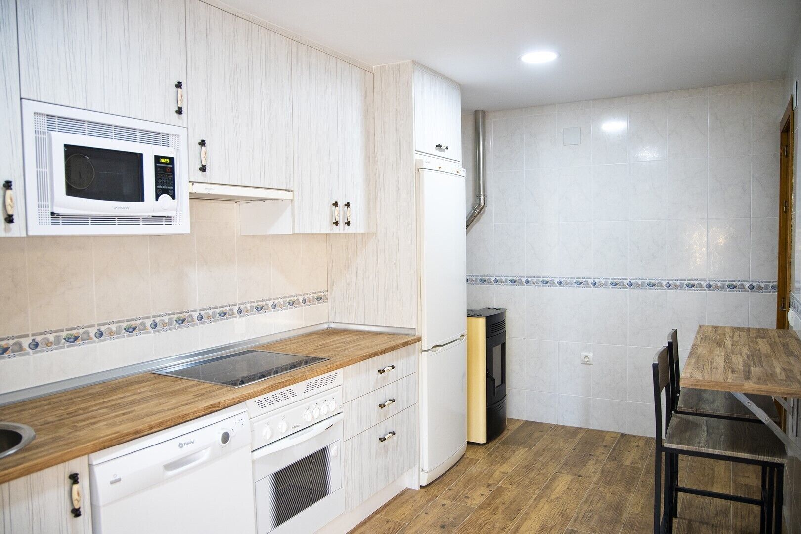 A kitchen with white cabinets, a microwave, a stove, and a refrigerator.