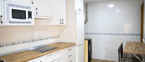 A kitchen with white cabinets, a microwave, a stove, and a refrigerator.