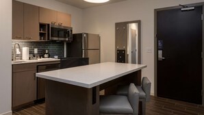 A modern kitchen with a central island, stainless steel appliances, and a dark door.